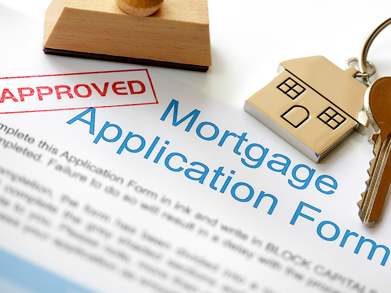 Approved Mortgage loan application with house key and rubber stamp