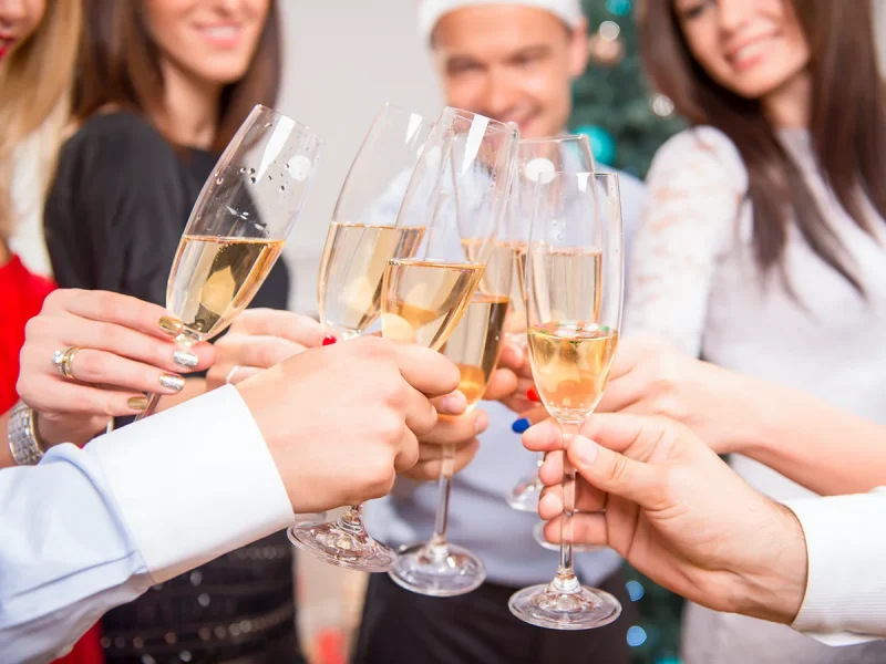 A group of friends clink champagne glasses to celebrate Christmas or the New Year