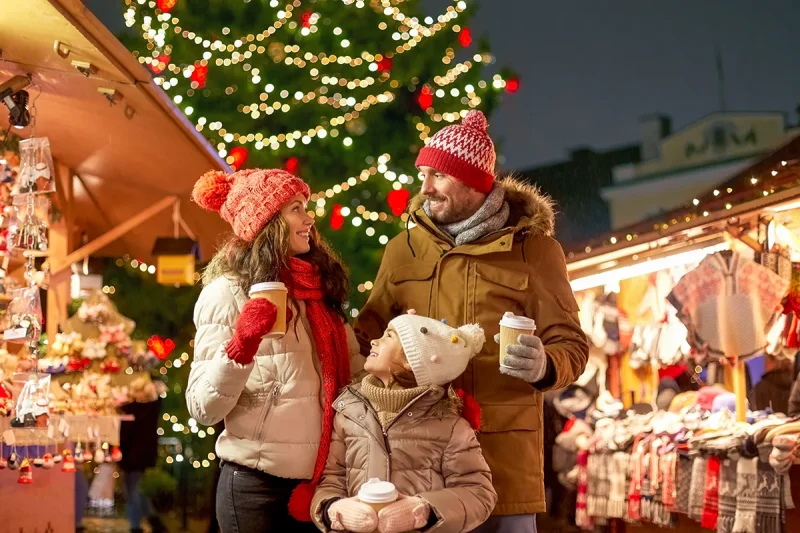 A couple and their child enjoy hot chocolate at a Christmas Market